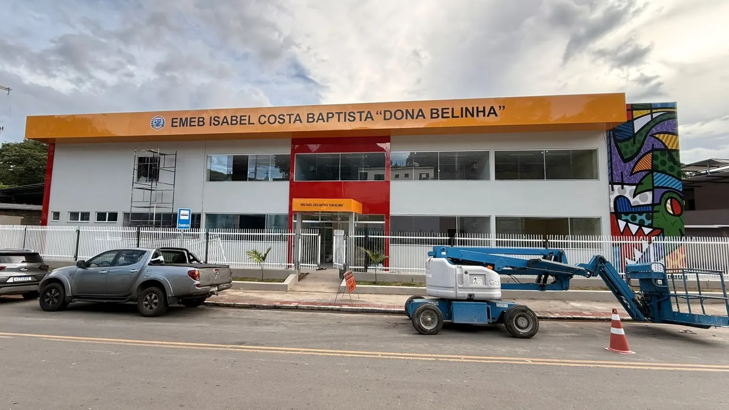 Fachada de escola municipal com painel e faixa instalados