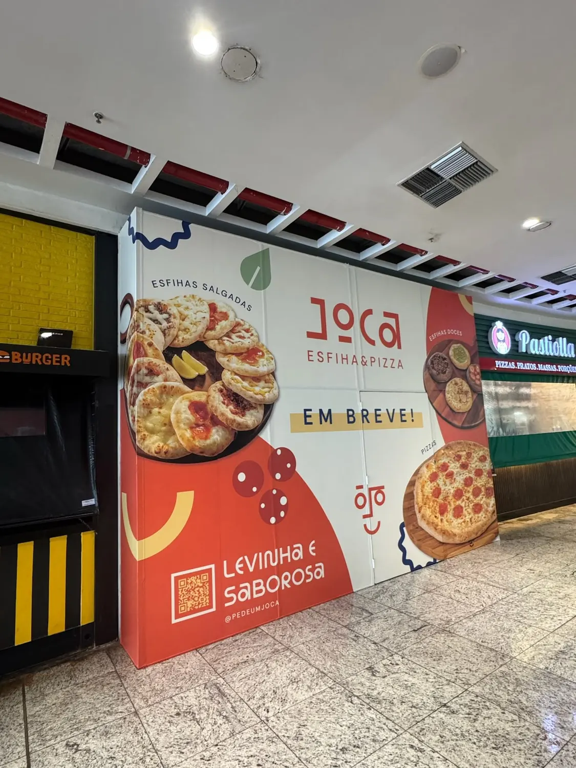 Tapume de loja em praça de alimentação com a marca Joca Esfiha e Pizza