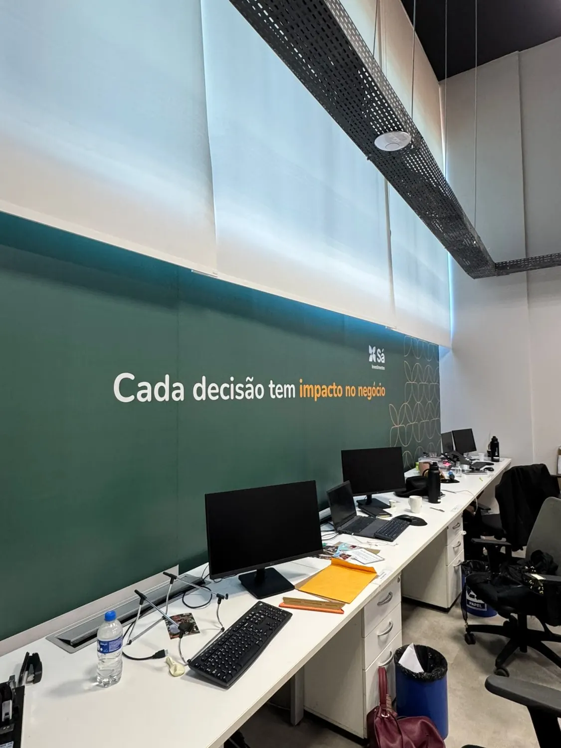 Sala de trabalho com parede verde e frase institucional