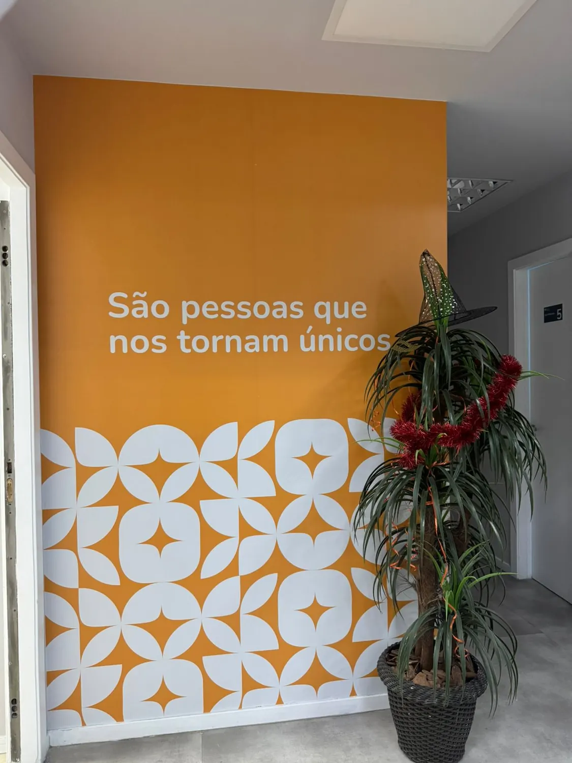 Parede laranja com grafismo e frase aplicada