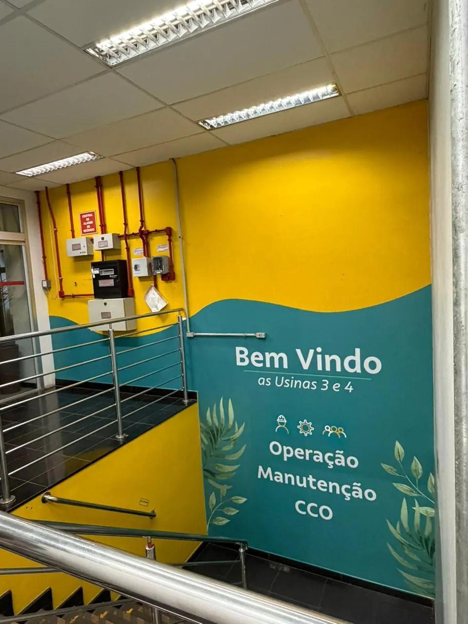 Recepção com parede amarela e verde e sinalização de boas-vindas