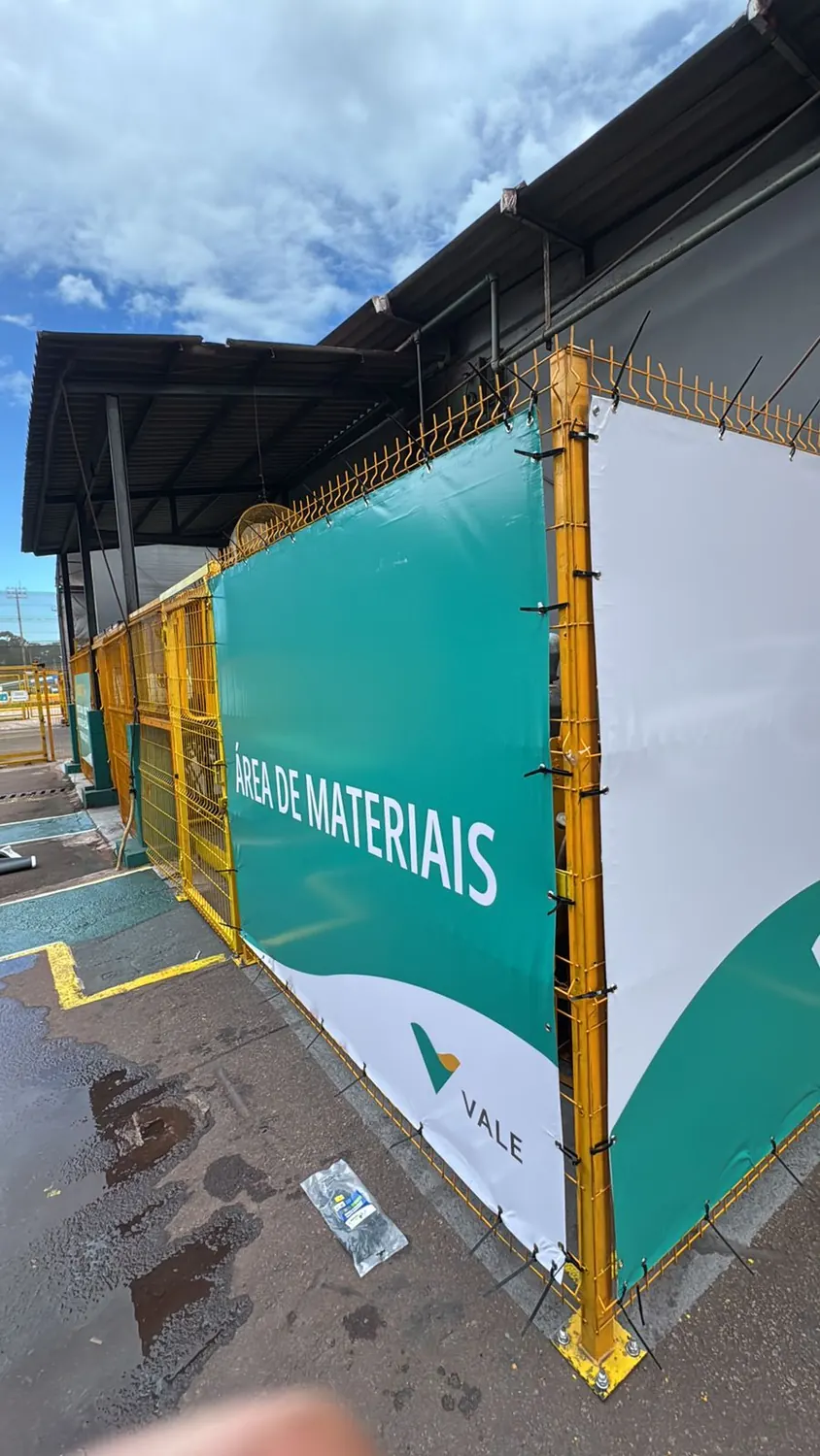 Tapume verde de área de materiais em pátio industrial