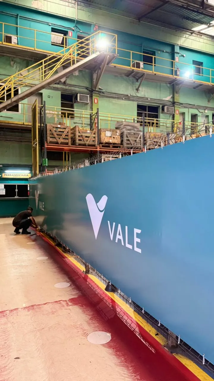 Tapume azul com marca aplicada dentro de galpão industrial